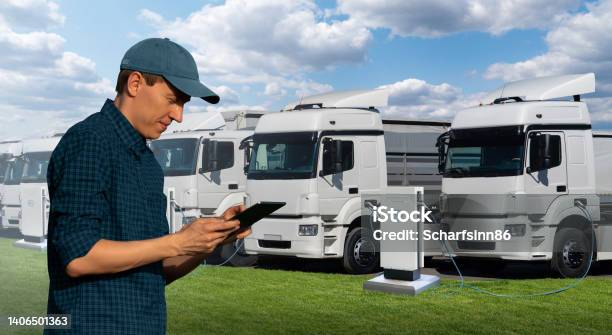 Fleet Manager With A Digital Tablet Stands Next To Electric Trucks Stock Photo - Download Image Now