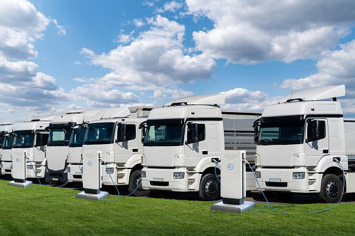 Row of electric semi trucks at charging stations for electric vehicles