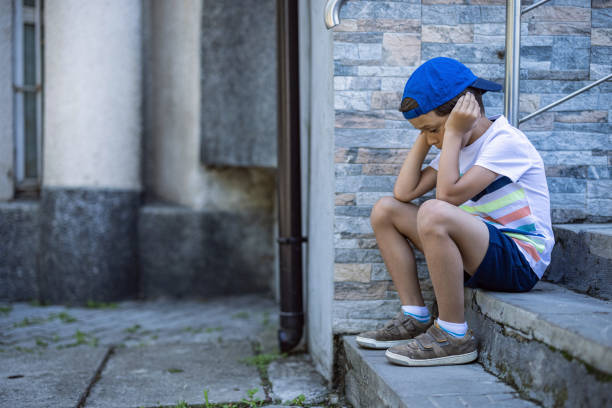 istock Kid sitting on stairs and feeling sad 1406501935