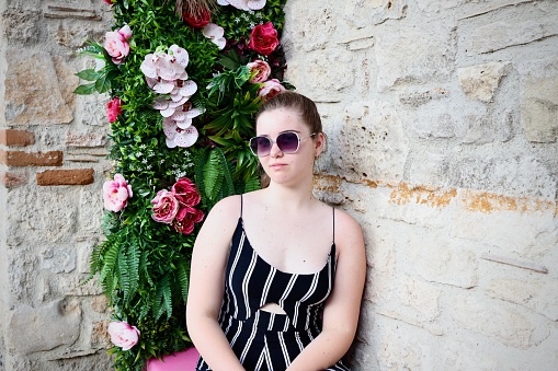 Girl with sunglasses sitting around the flowers