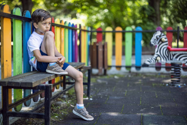 istock Kid sitting on a bench and feeling lonely 1406502899