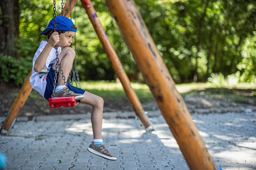 Little boy feeling lonely on a swing