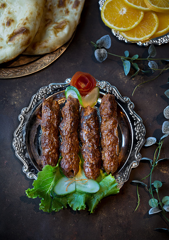 Beef Seekh Kabab with roti, salad and lemon slice served in dish isolated on dark background top view