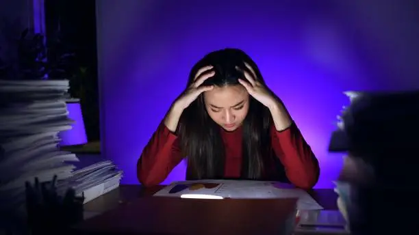 Asian businesswoman working hard late hours with a lot of document at home. Busy and exhausted of work overtime at night.