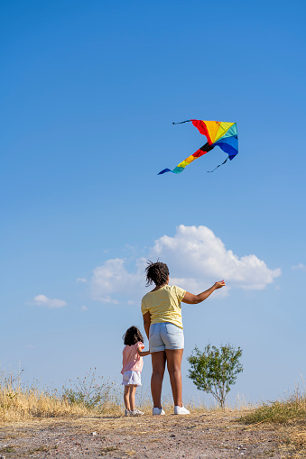mother teaching her little daughter to fly the colorful kite