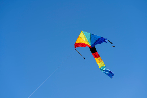 closeup of rainbow kite flying in blue sky on a summer day
