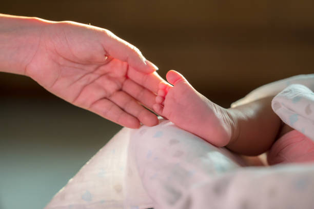 istock hand touching newborn baby foot with love 1406509261