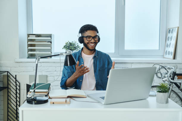 Happy young African man having web conference and gesturing stock photo