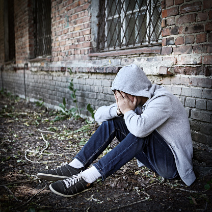 Toned Photo of Sad Teenager sit by the Brick Wall outdoor