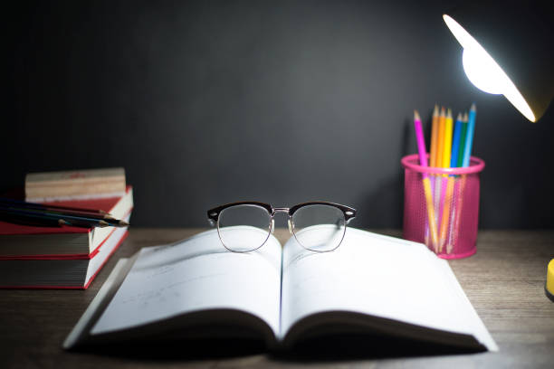 istock Reading table at night, Glasses placed on open book, And lighting from lamps, Copy-space 1406511908
