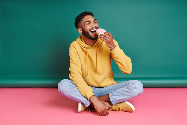 Cheerful African man enjoying doughnut