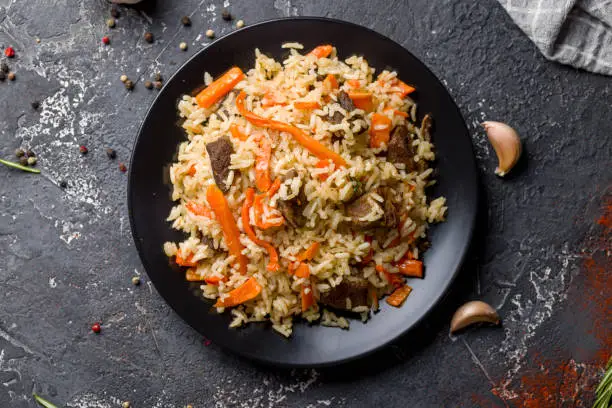 pilaf with beef and carrot top view on dark table