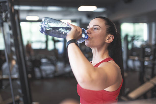 istock Young woman drinking water from bottle in gym 1406514547