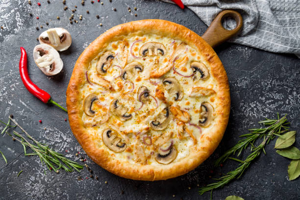istock Pizza with chicken and mushrooms with cheese top view on dark stone table 1406515367