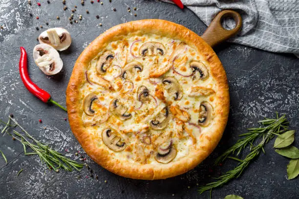 Photo of Pizza with chicken and mushrooms with cheese top view on dark stone table