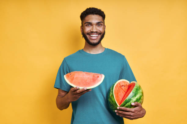 istock Young African man holding watermelon and smiling 1406515437