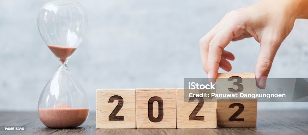 hand flip block 2022 to 2023 text with hourglass on table. Resolution, time, plan, goal, motivation, reboot, countdown  and New Year holiday concepts 2022 Stock Photo