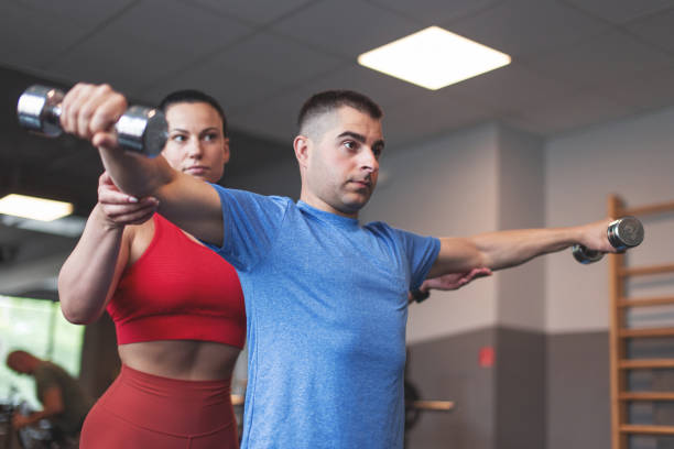 personal trainer woman holding clients elbow during workout by dumbbells - secrecy instructor exercising individuality imagens e fotografias de stock