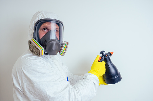 pest control worker spraying pesticides with sprayer in apartment copy spase white walls background .