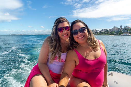 Women in bikinis on top of a boat against the sea in the background. Salvador, Bahia, Brazil.