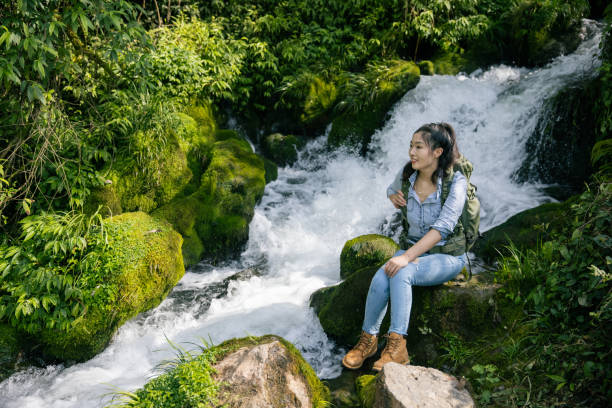 istock Female hiker sitting by the waterfall have a rest 1406519202
