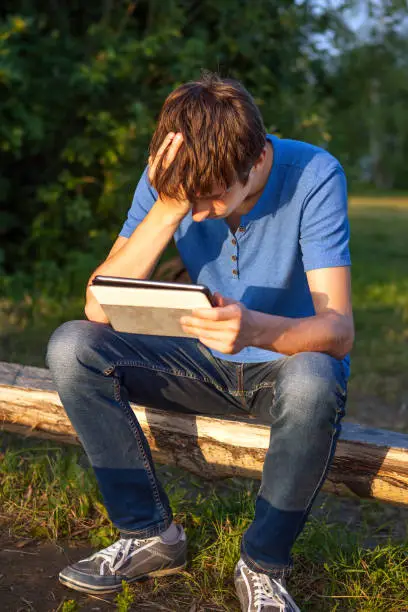 Sad Young Man with Tablet Computer on the Wooden Bench