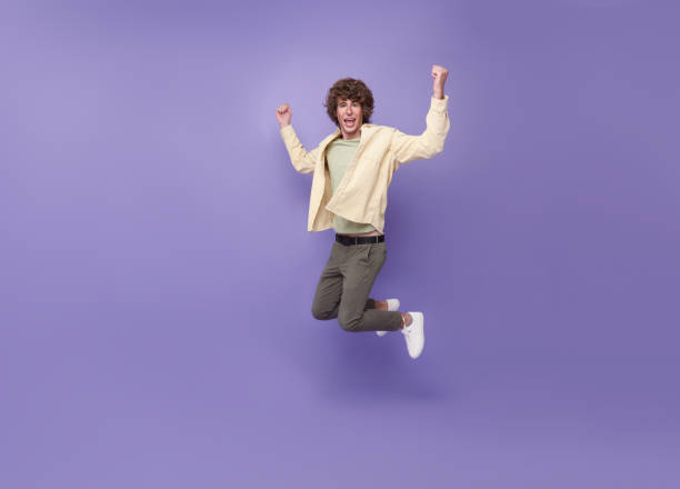 istock Cheerful guy jumping having fun rejoicing isolated on purple background 1406519336