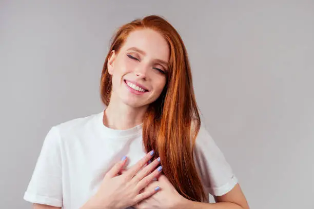 happy redhair ginger woman in studio background feeling heart thanks .