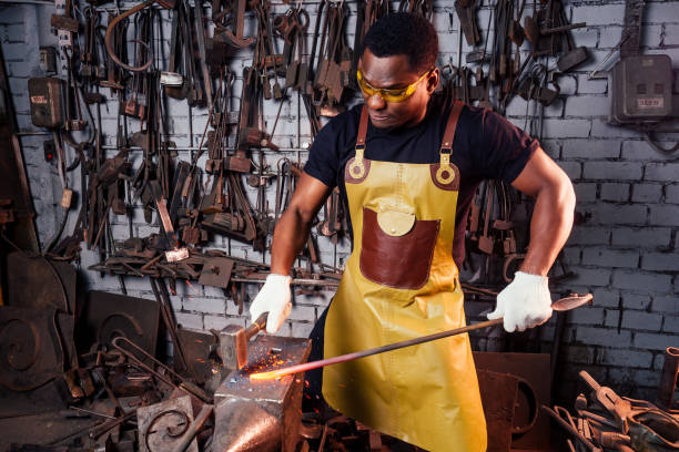 istock handsome african american blacksmith male worker working in workshop,wearing leather apron 1406519680