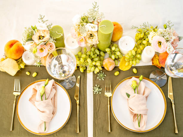 Festive colourful table setting. Restaurant, wedding, party decorated with flowers, candles, fruits and leaves. Midsummer or autumn mood event, romantic dinner. Florist decorator occupation.