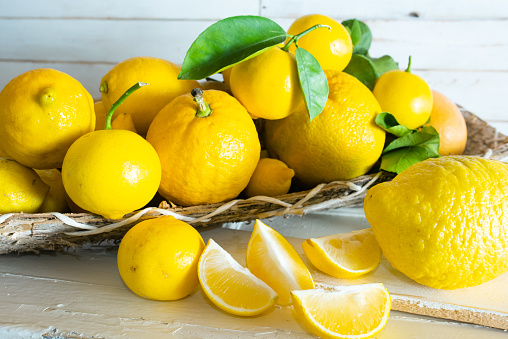 Whole lemon and halves of ripe fresh fruit with leaves on dark background. With copy space