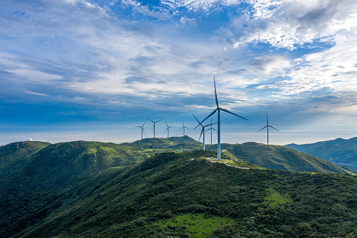 clean energy concept, photovoltaic panels and wind turbines in the light of the rising sun