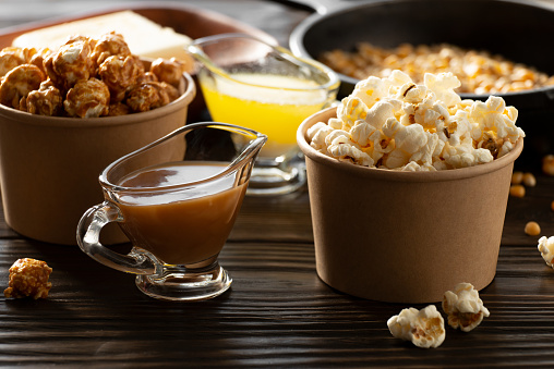 Paper buckets with butter and caramel popcorn on kitchen table