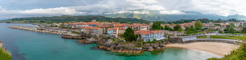 Panoramic view of Llanes, with the Sablon beach, the breakwater of the cubes of memory, and the Cantabrian mountain range in the background.