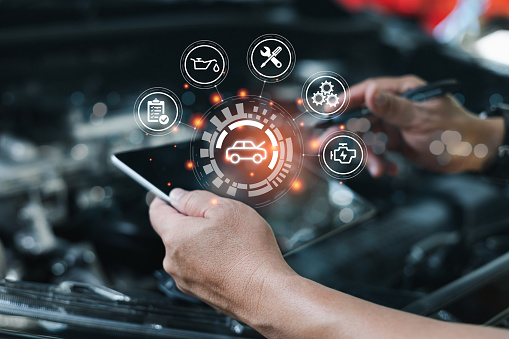 Auto mechanic using digital tablet front of cars
