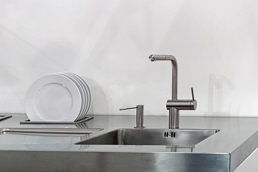 Modern kitchen faucet at stainless steel sink with built in dish dryer