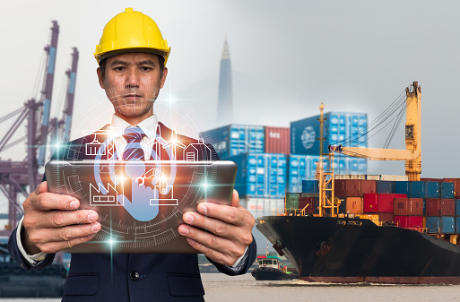 A businessman uses a digital tablet for logistic network distribution and smart transportation, for networking intelligent logistics of container cargo ships, logistic import-export, and industrial.