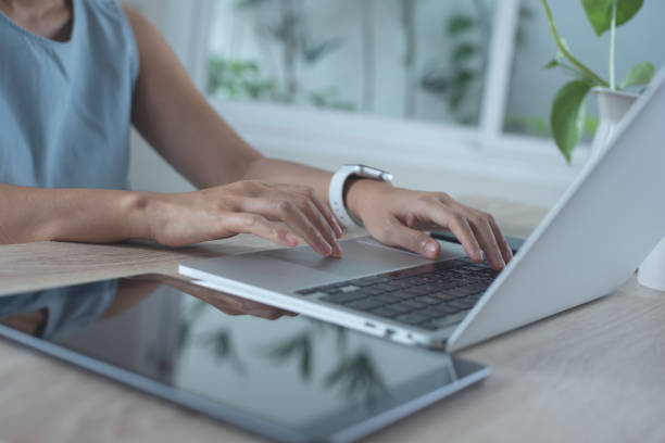 istock Closeup image of a business woman's hands working and typing on laptop computer keyboard on glass table at office 1406530619