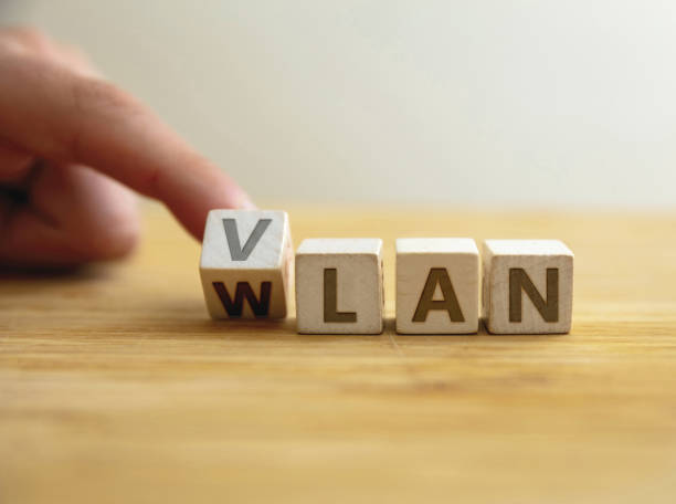 istock Vlan to wlan network type concept. Finger flips letter at wooden cube changing the word vlan to wlan 1406532028
