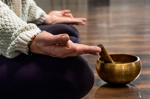 woman meditation with Tibetan singing bowl during practicing yoga on mat.