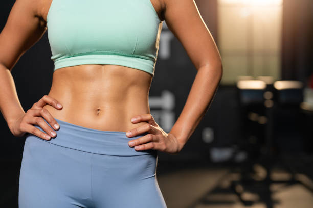 primer plano de la mujer fitness mostrando músculos abdominales. culturista femenina atlética que muestra abdominales fuertes en el gimnasio - músculo abdominal fotografías e imágenes de stock