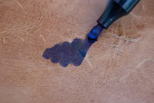 Permanent blue marker scribbling on brown leather, blurred soft focus macro