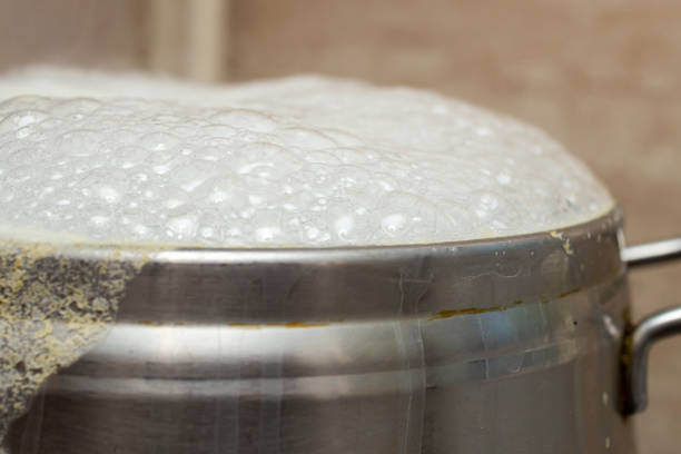 silver inox pot boiling over with white  bubbles, close up macro