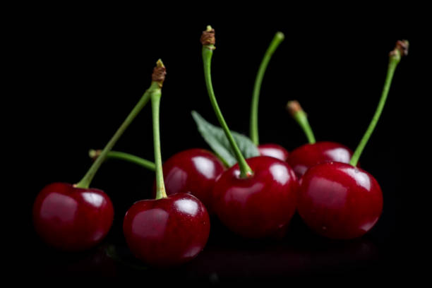 istock Red cherry berries on a black background with mirror. Three cherries 1406536451