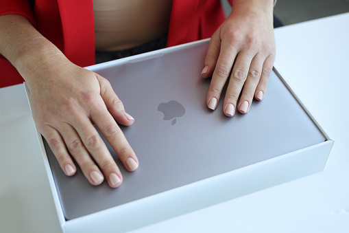 Minsk, Belarus, April 1, 2022: Female hands on new MacBook Air. Laptop for fast work concept