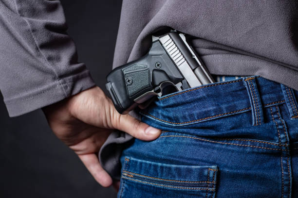 istock Problems of terrorism and the unauthorized application of shooting iron. Person holds hide a handgun behind a back. 1406537853