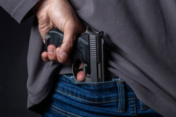 istock Problems of terrorism and the unauthorized application of shooting iron. Person holds hide a handgun behind a back. 1406537860