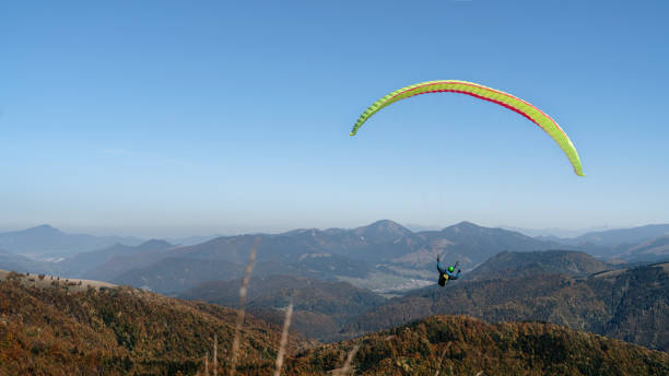 istock Paragliders flying in the blue sky with mountain in background. 1406540093