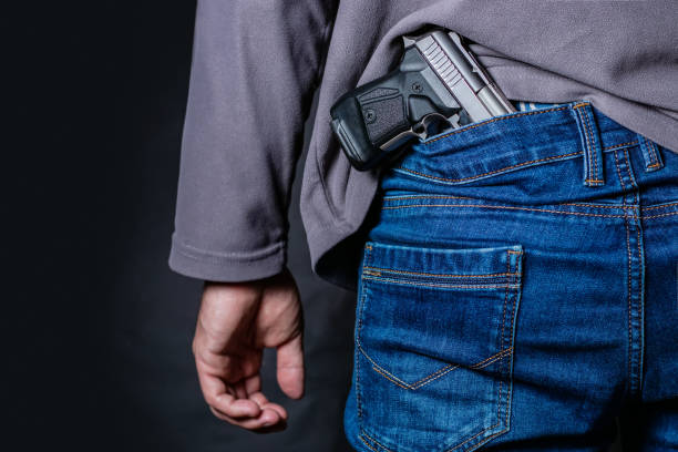 istock Problems of terrorism and the unauthorized application of shooting iron. Person holds hide a handgun behind a back. 1406540595