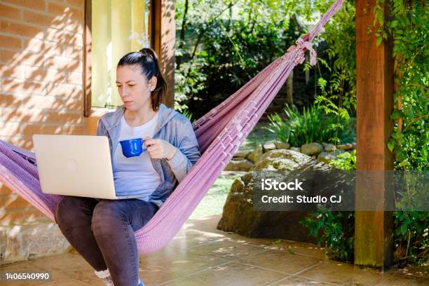 Young Womanworking Or Studying Sitting In Hammock On Balcony Of Chalet During Vacation Stock Photo - Download Image Now
